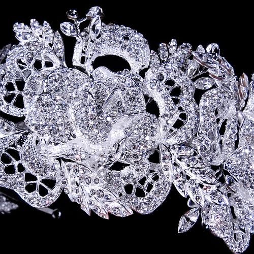 Close-up of a decorative silver brooch with intricate designs on a black background